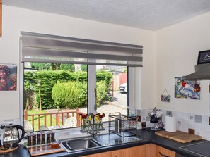 A modern kitchen with a large window, stainless steel sink, and a wooden countertop. - 2 bedroom accommodation in Prestatyn (Prestatyn)