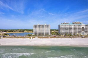 A beachfront hotel with multiple floors, a pool, and a beach area. - Wave Whisperer: Family Beachfront Hideaway (Destin)