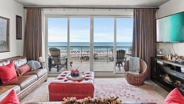 A living room with a large sliding glass door leading to a balcony with a view of the beach. - Wave Whisperer: Family Beachfront Hideaway (Destin)