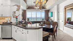 A spacious kitchen with a large island, white cabinetry, and a view to the outside. - Wave Whisperer: Family Beachfront Hideaway (Destin)