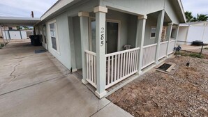 A single-story house with a porch, a mailbox, and a number 285 on the door.