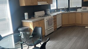 A modern kitchen with wooden cabinets, a gas stove, a microwave, and a glass dining table with chairs.