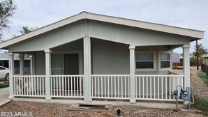 A single-story building with a flat roof, a covered porch with white railings, and a small attached garage.