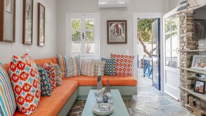 A living room with a sofa, pillows, a coffee table, and a stone fireplace. - Holiday Home 'Waterfront Masterpiece' with Sea View, Wi-Fi and Air Conditioning (Tinos)