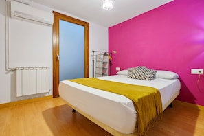 Een slaapkamer met een bed, een radiator, een deur en een roze muur.