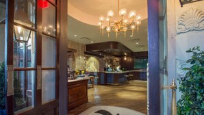 A hotel lobby with a wooden reception desk, a bar area, and a chandelier.