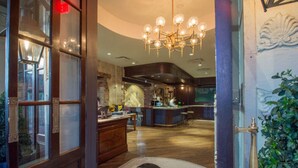 Un hall d’hôtel avec un comptoir d’accueil en bois, un espace bar et un lustre.