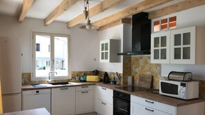 A kitchen with white cabinets, a black oven, a microwave, and a window with a view. - Holiday Home 'Jardin Arboré, Belle Maison Piscine' with Private Pool, Terrace and Wi-Fi (Saint-Trojan-les-Bains)
