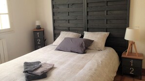 A bedroom with a bed, two nightstands, a window, and a wall-mounted headboard. - Holiday Home 'Jardin Arboré, Belle Maison Piscine' with Private Pool, Terrace and Wi-Fi (Saint-Trojan-les-Bains)