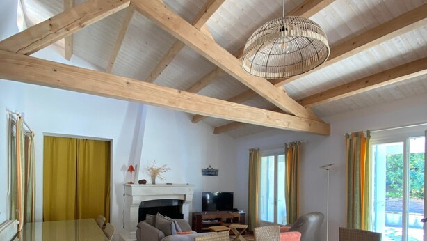 A spacious living area with a high wooden ceiling, a dining table surrounded by wicker chairs, a sofa, and a television. - Holiday Home 'Jardin Arboré, Belle Maison Piscine' with Private Pool, Terrace and Wi-Fi (Saint-Trojan-les-Bains)