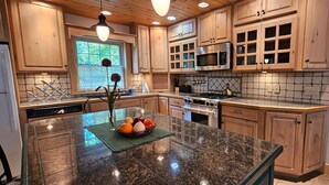 Una cocina con armarios de madera, encimera de granito, estufa de acero inoxidable y microondas.
