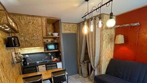 A compact living space with a kitchenette, a dining area, a sofa, and a coffee table.