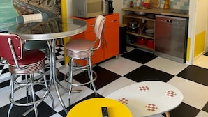 Una cocina compacta con zona de comedor, un cuadro en la pared y suelo a cuadros.