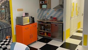 Una cocina compacta con piso a cuadros, un microondas, un fregadero y un refrigerador.