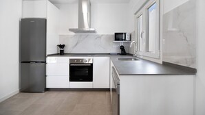 A modern kitchen with a stainless steel refrigerator, oven, microwave, and a large window.