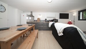 Eine moderne Küche mit einem Holztisch, einer Bank und einem schwarzen Sofa mit weißer Decke.