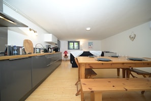 A modern kitchen with grey cabinets, a wooden countertop, and a dining area with a wooden table and benches.