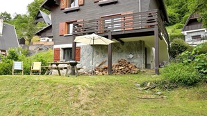 Ein zweistöckiges Haus mit Balkon, Grill und Holzstapel.