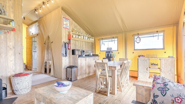Un intérieur chaleureux et rustique avec un coin repas en bois, une petite cuisine et une douche.