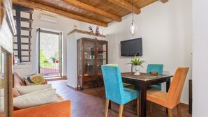 A dining area with a wooden table, blue chairs, a television, and a cabinet with glass doors.