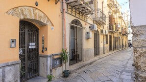 A narrow street with buildings featuring arched doorways and balconies.