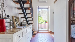 A hallway with a staircase, a kitchen counter, and a door leading to an outdoor area.