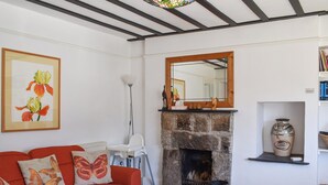 Un salon avec un canapé rouge, une cheminée, un miroir et une bibliothèque.