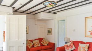 Un salon avec deux canapés rouges, une table basse en bois et une porte.