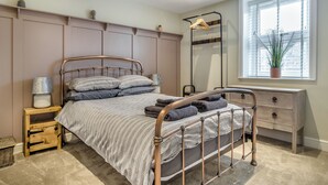 Ein Schlafzimmer mit Bett, Nachttisch, Kommode und einem Fenster mit Jalousien.