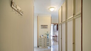 Een gang met een vis aan de muur, een bord met een welkomstboodschap, een tafeltje met een vaas en een kast.
