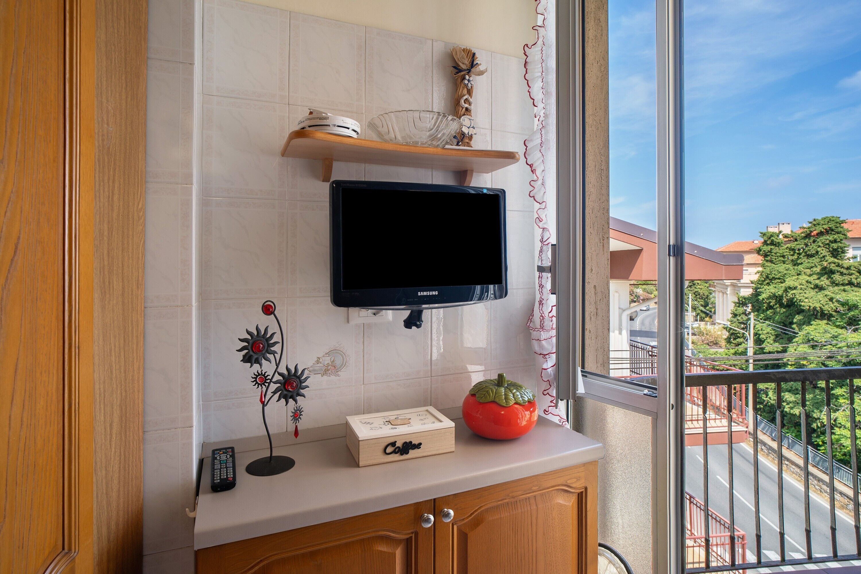 Una cocina con televisor, un dispensador de café y una planta decorativa.