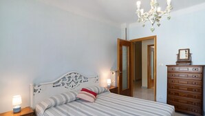 Een slaapkamer met een bed, nachtkastje, kaptafel en een kroonluchter.