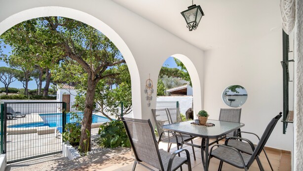 Un patio exterior con mesa y sillas, una piscina y vistas al mar.