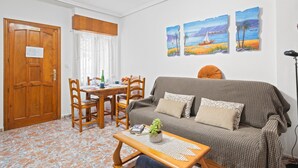 En stue med sofa, sofabord, spisebord med stole, og en dør med teksten 'SALIDA'.