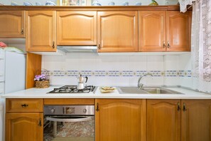 Una cocina con armarios de madera, encimera blanca, estufa, fregadero y lavavajillas.