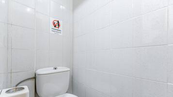 Une salle de bain équipée de toilettes, d’un bidet et d’un panneau indiquant qu’il est interdit de fumer.