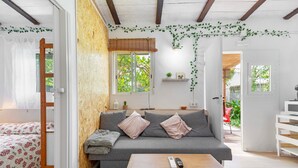A cozy living room with a sofa, a wooden table, and a bed with floral bedding.
