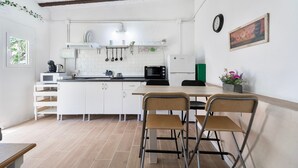 A kitchen with white cabinets, a microwave, a sink, and a dining area with two chairs.