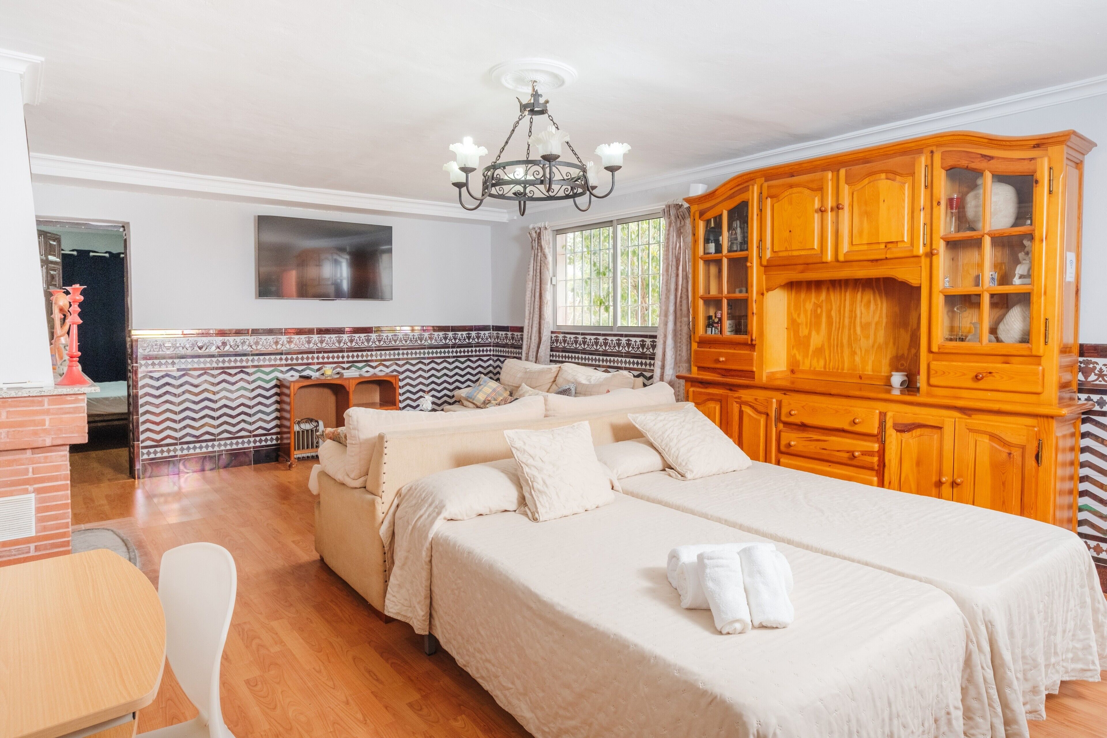 Una habitación de hotel con una cama grande, un armario de madera y un televisor en la pared.