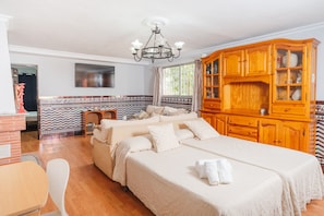 A hotel room with a large bed, a wooden cabinet, and a television on the wall.