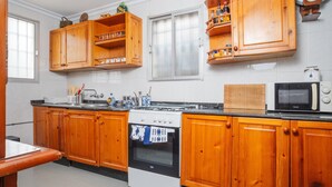 Una cocina con armarios de madera, estufa, microondas y una ventana con persianas.