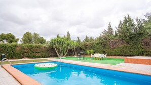 Piscina rectangular con una alfombra flotante, rodeada por un borde de ladrillo.
