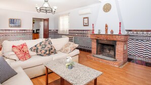 Una sala de estar con sofá, mesa de centro, chimenea y baldosas estampadas.