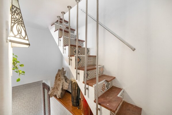 Eine Treppe mit gemusterten Fliesen, einer Metallhandläufe und einer hängenden Pflanze.