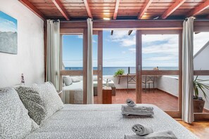 Ein Schlafzimmer mit Bett, Meerblick und Balkon mit Gartenmöbeln.