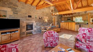 A rustic interior with a stone fireplace, wooden beams, a television, and a dining area. - Holiday Home 'Le Calmadou' with Mountain View, Private Terrace and Wi-Fi (Formiguères)