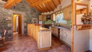 A kitchen with stone walls, wooden beams, and a curved island. - Holiday Home 'Le Calmadou' with Mountain View, Private Terrace and Wi-Fi (Formiguères)