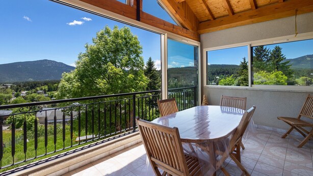 A balcony with a wooden table and chairs, large windows with a view of greenery and mountains. - Holiday Home 'Le Calmadou' with Mountain View, Private Terrace and Wi-Fi (Formiguères)