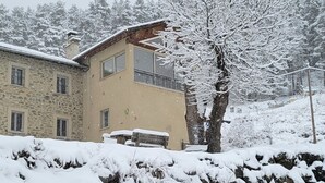 A stone building with a balcony, a snow-covered tree, and a bench in front. - Holiday Home 'Le Calmadou' with Mountain View, Private Terrace and Wi-Fi (Formiguères)