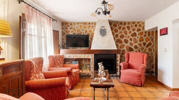 Una sala de estar con chimenea, pared de piedra y dos sillones.
